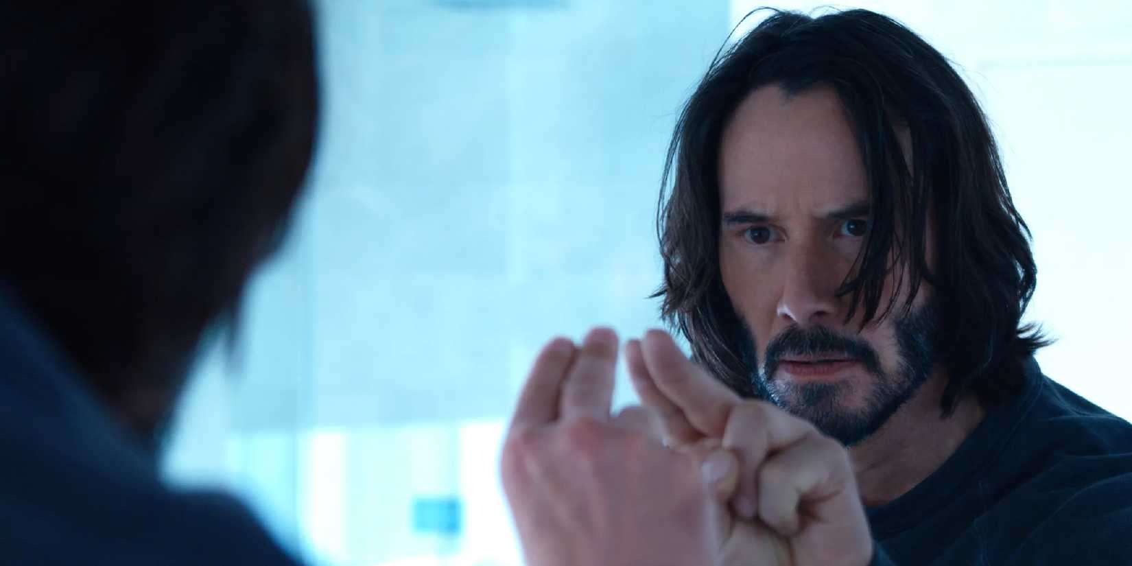 Keanu Reeves looking at himself in a mirror in The Matrix Resurrections