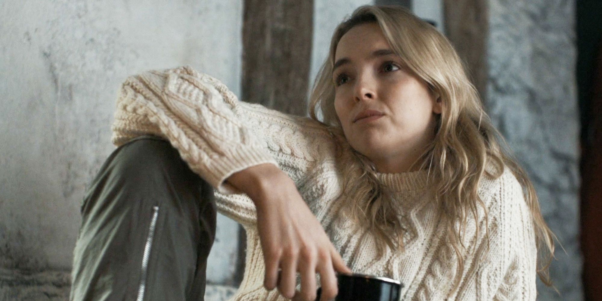 Villanelle lounging in a sweater while drinking from a mug