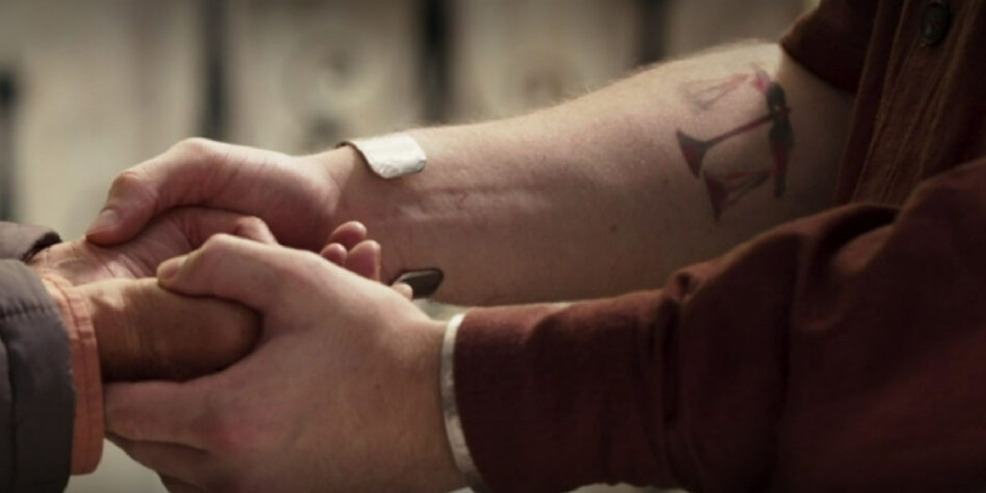 Arthur Harrow holding a woman's hands while his tattoo moves 