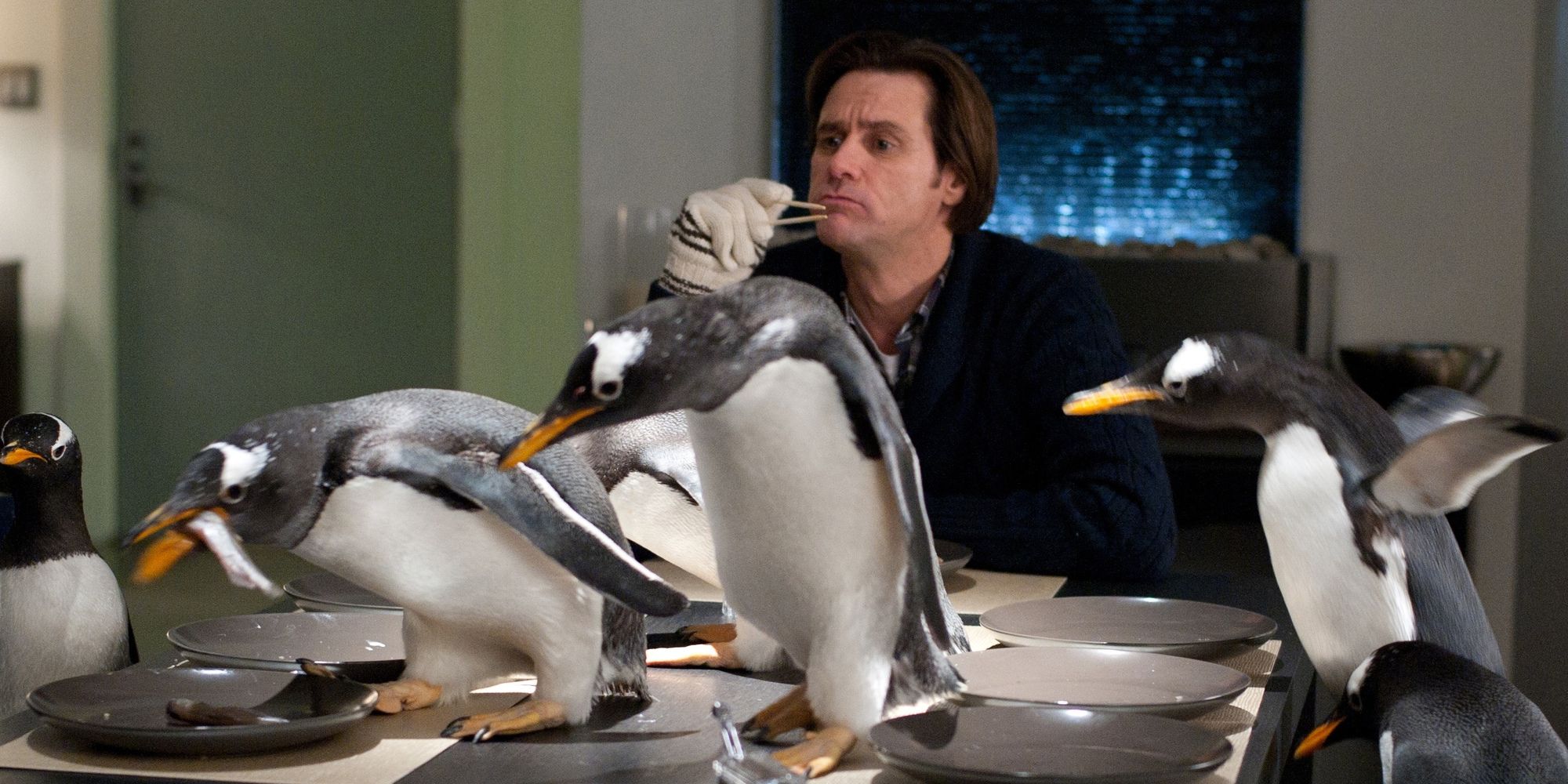 Jim Carrey as Mr. Popper at a dinner table covered in penguins