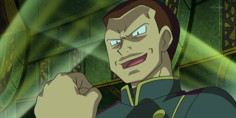 Giovanni raising a fist with supervillain lighting on his face