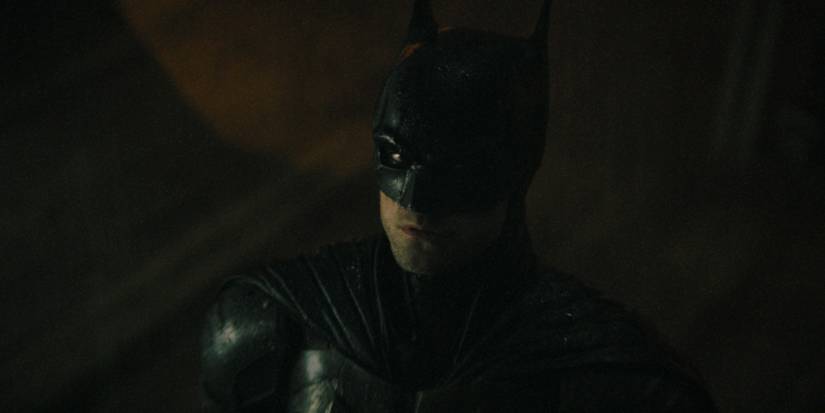 Robert Pattinson looking up in the rain in The Batman