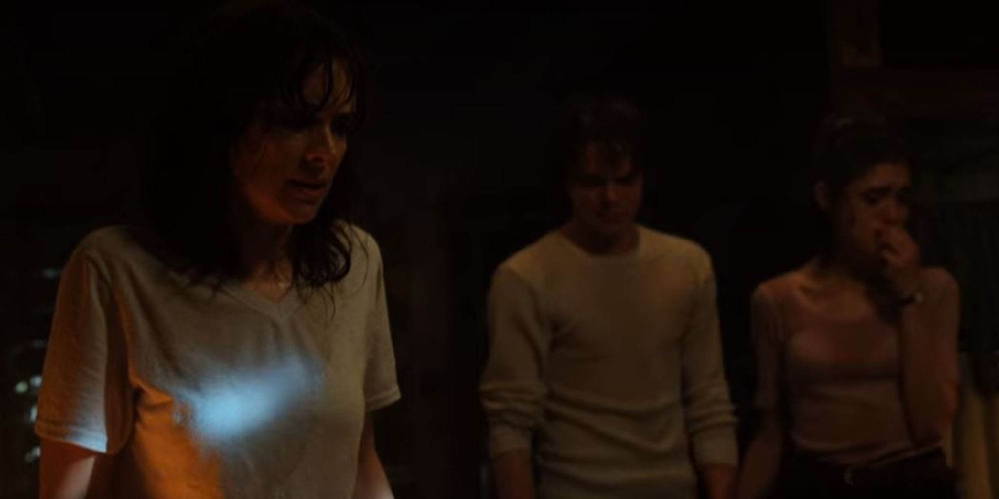 A sweaty Joyce standing with Jonathan and Nancy in Hopper's cabin in season 2