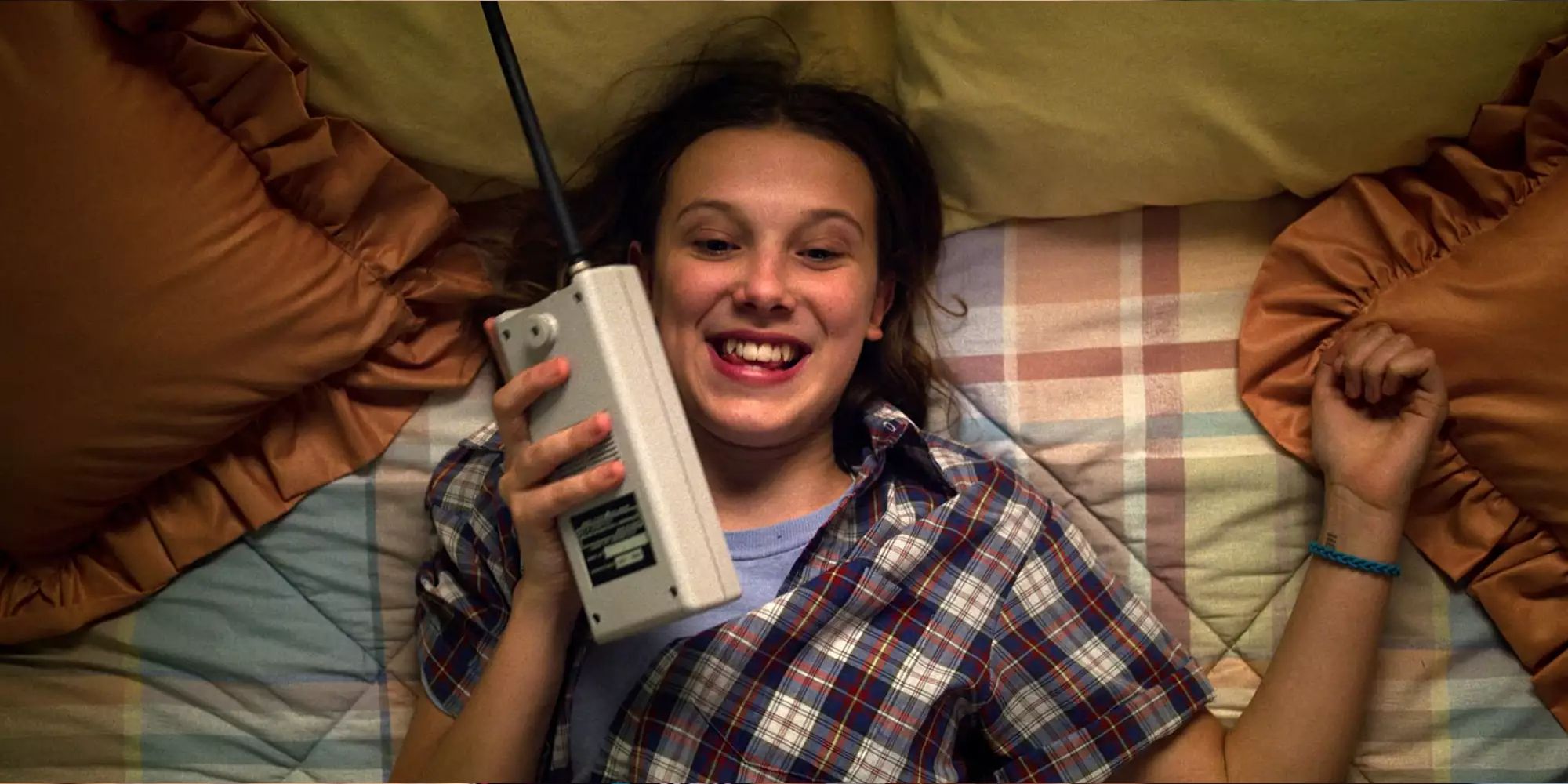 Eleven smiling while using her walkie-talkie in bed in season 3