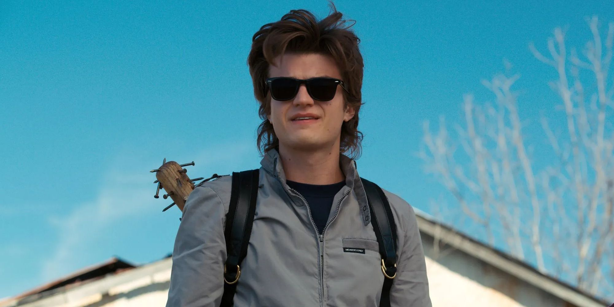 Steve Harrington wearing shades and carrying his baseball bat during the day