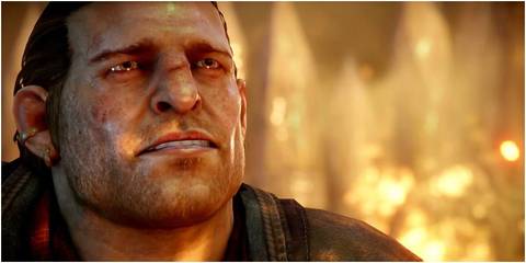Close up shot of Varric surrounded by fire and frowning from Dragon Age: Inquisiton
