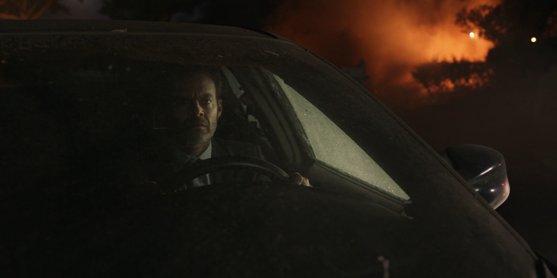 Barry Berkman sits in his car with a house burning behind him in Barry