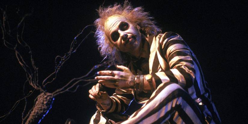 Michael Keaton as Betelgeuse sitting on a grave in Beetlejuice