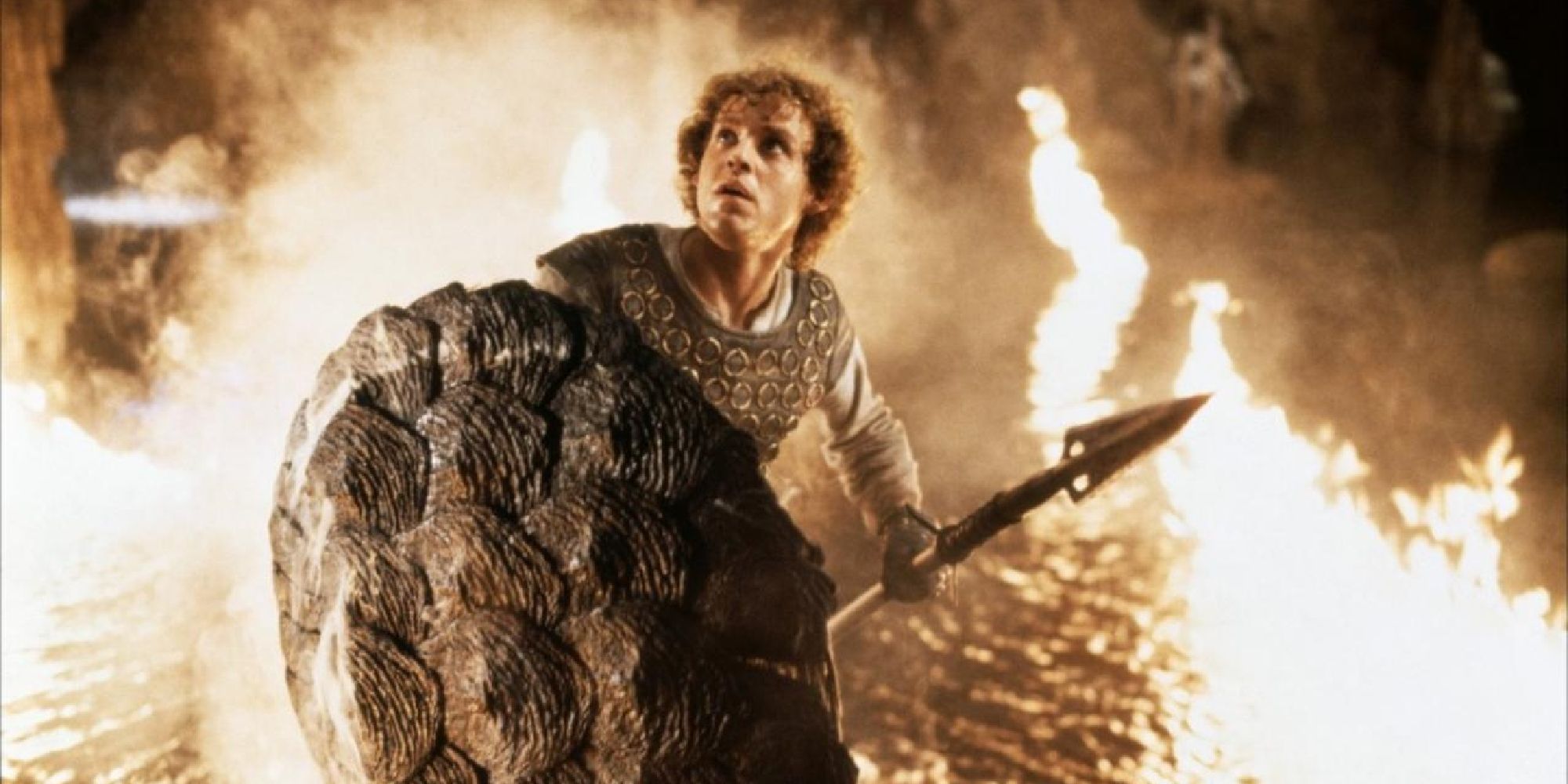 Peter MacNicol carrying a spear and shield surrounded by fire in Dragonslayer