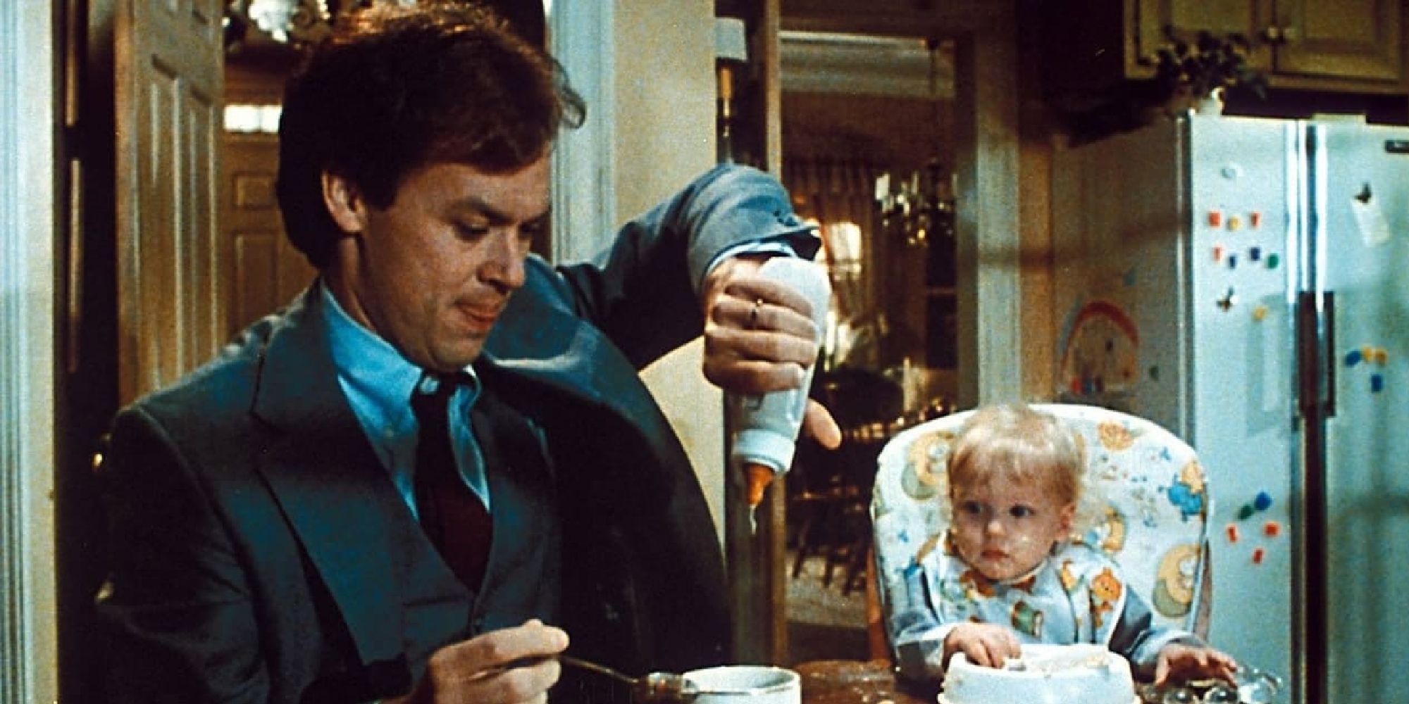 A baby watching Michael Keaton pour baby formula into his coffee in Mr. Mom