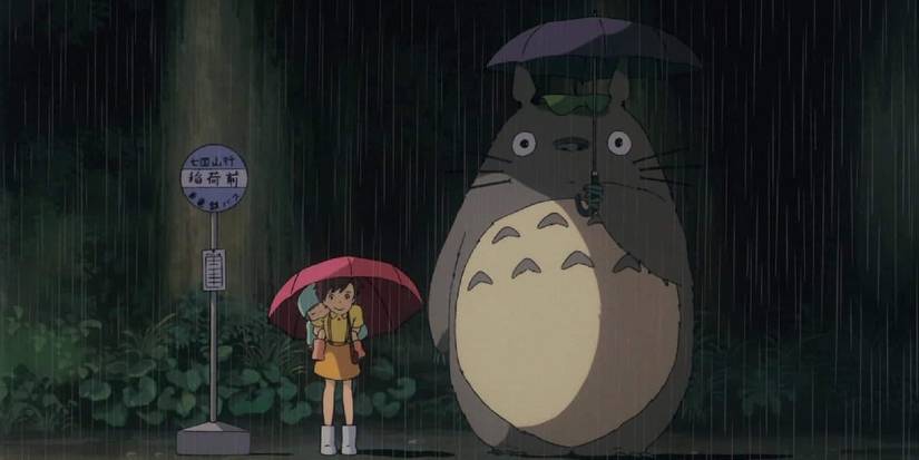 Satsuki carrying Mei on her back while standing next to Totoro in the rain