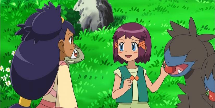 Iris and Axew reuniting with Iris's childhood friend, Shannon, who feeds apples to a Zweilous