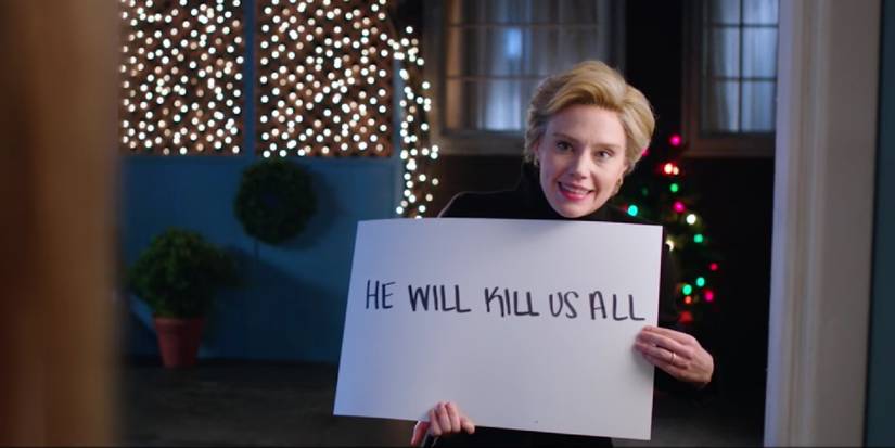 Kate McKinnon as Hillary Clinton holding up cards that reads "He will kill us all"