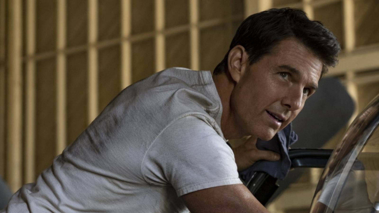 Tom Cruise white t-shirt in shop Top Gun Maverick looking at camera