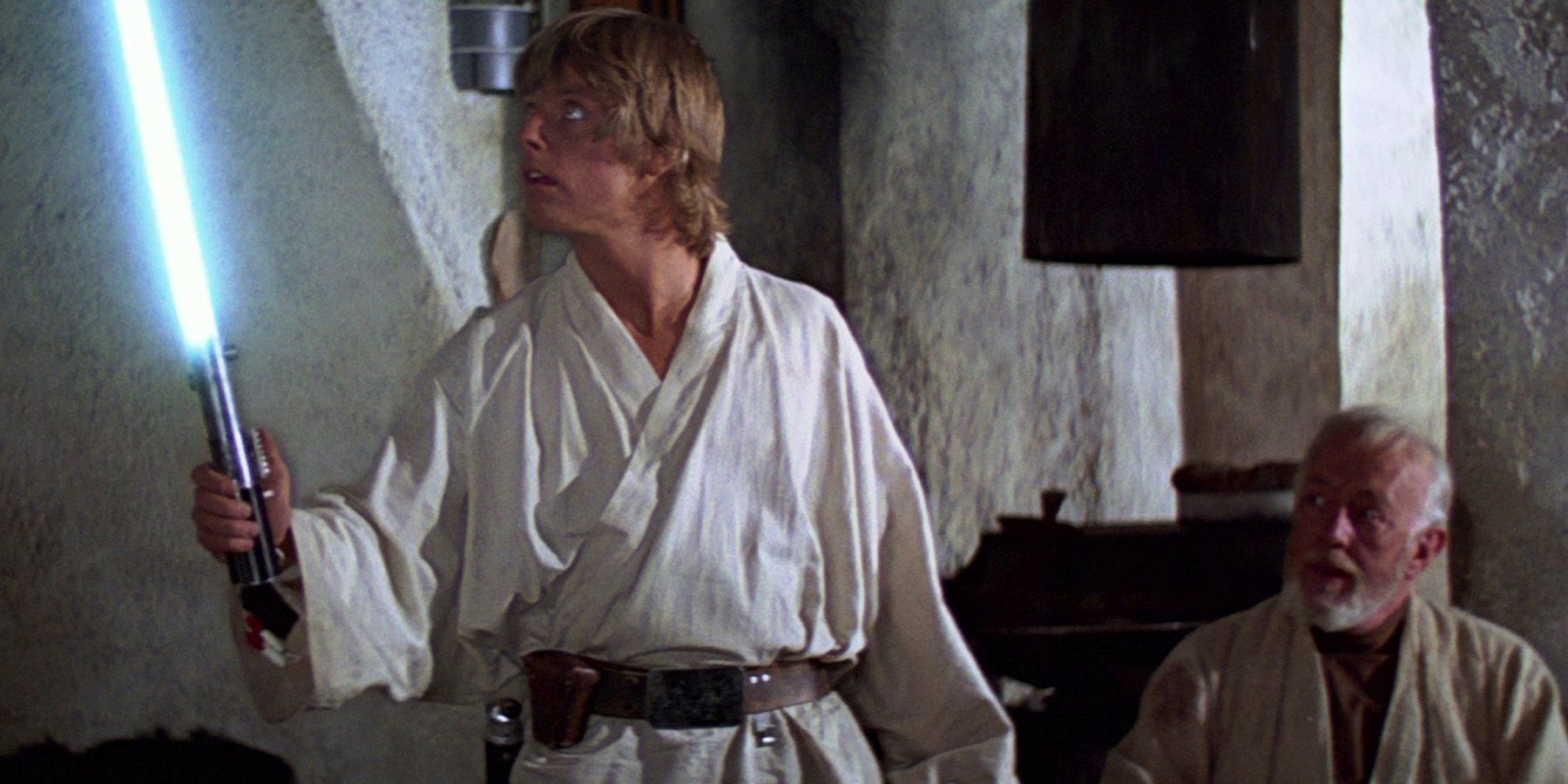 Luke holding a lightsaber while Obi-Wan watches in Star Wars A New Hope