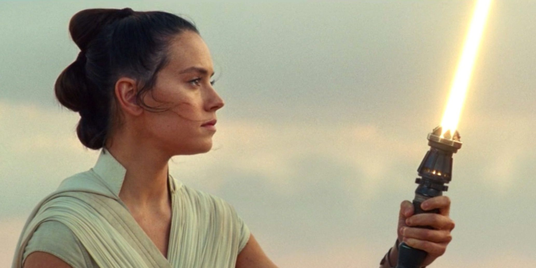 Rey holding her new lightsaber in Star Wars The Rise Of Skywalker
