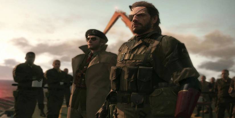 Venom Snake standing with Master Miller beside a squad of soldiers