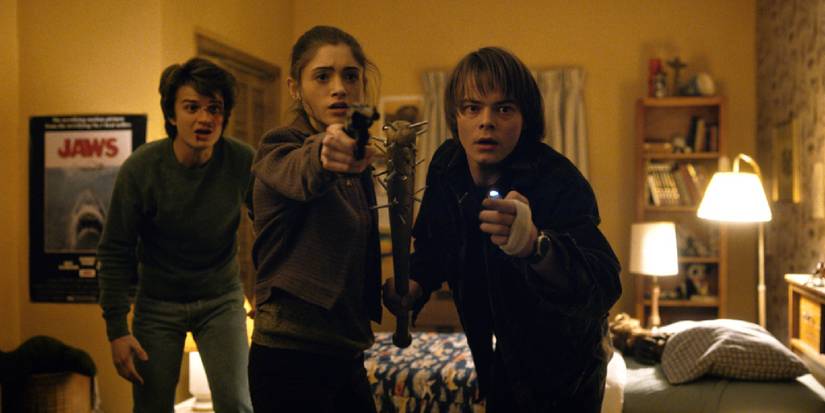 Steve stands behind Nancy with a gun and Jonathan with the spiked bat in the Byers house in season 1