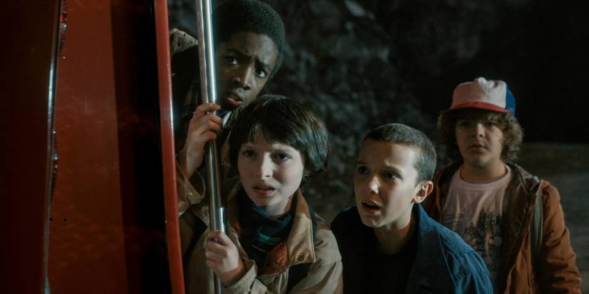 Lucas, Mike, Eleven, and Dustin standing near a firetruck in a quarry in season 1