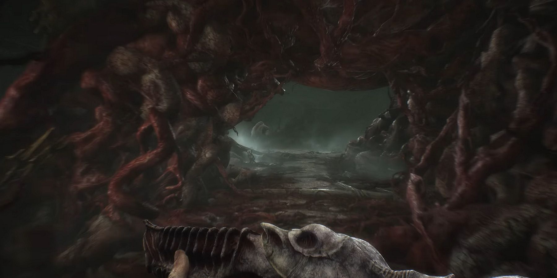 An image from Scorn showing the player holding a weapon as they enter a body-horror tunnel.