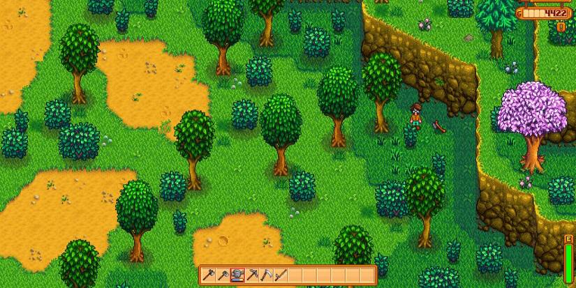 The player standing next to an axe in the middle of a forest in Stardew Valley