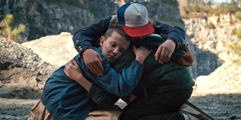 Eleven, Dustin, and Mike hug in Stranger Things