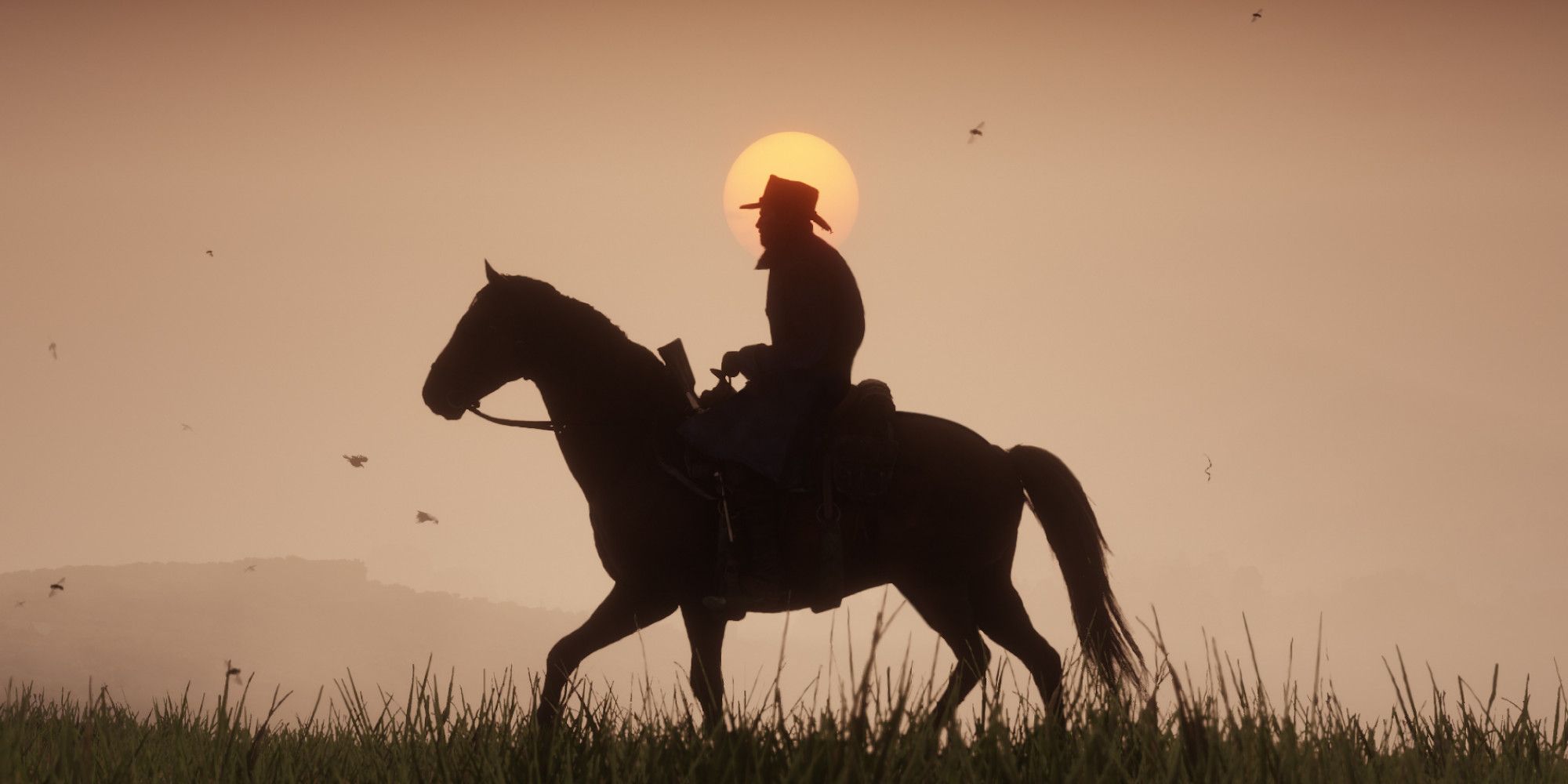 A cowboy rides a horse in front of a sunset