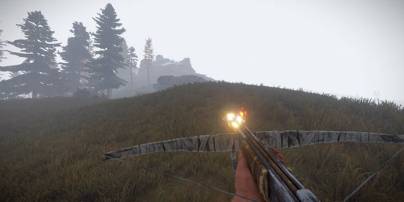 A player walking across a foggy hill in Rust holding a crossbow with a Fire Arrow equipped