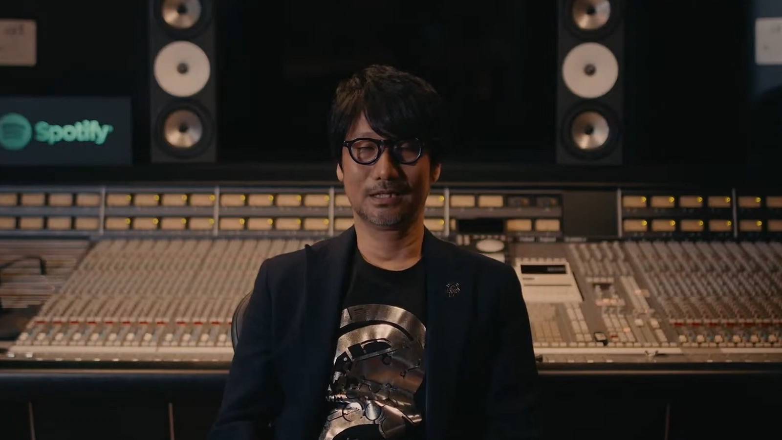 An image of Hideo Kojima sat in front of a studio mixing desk.