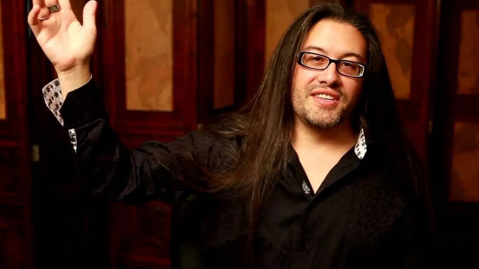 A photo of Doom co-creator John Romero holding up his right hand.