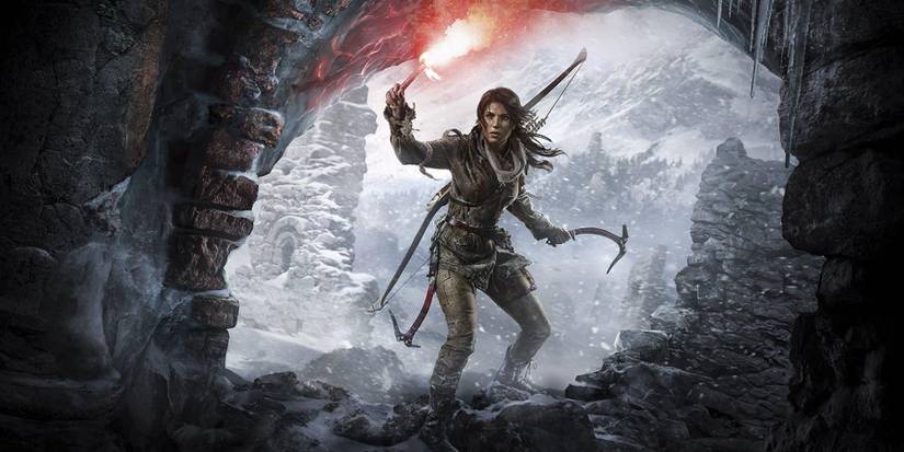 Lara Croft looking in a cave while holding a flare and a climbing axe in Rise of The Tomb Raider