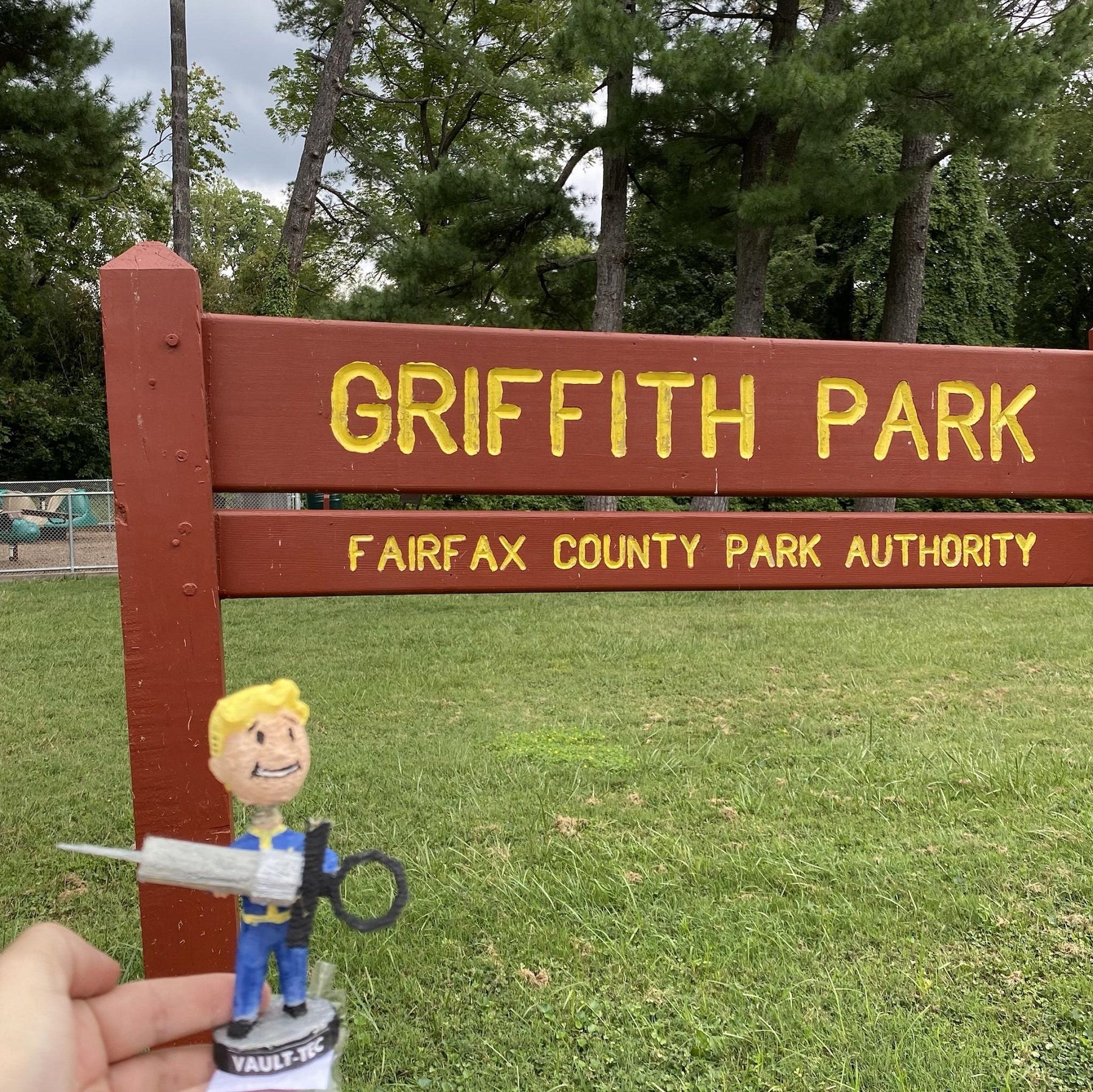 Daytime photo of a Fallout 3 bobblehead next to the Griffith Park sign.