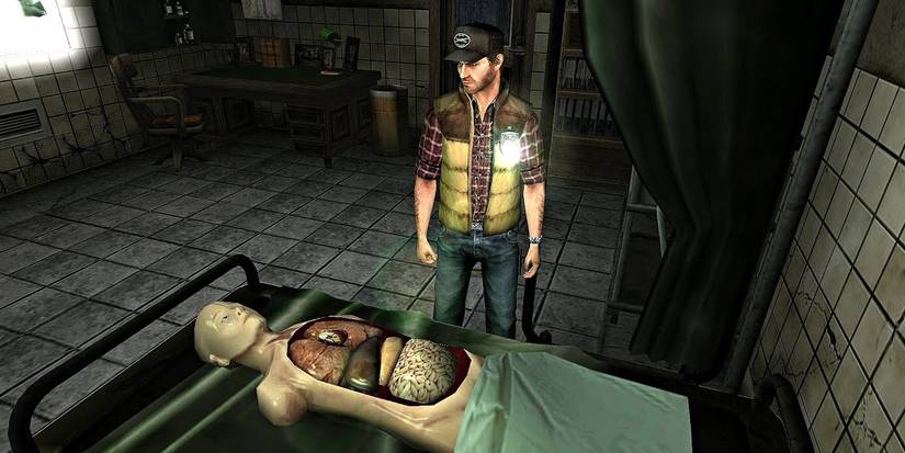 A man stands next to a hospital bed, where an anatomical body lies, fake organs on display.