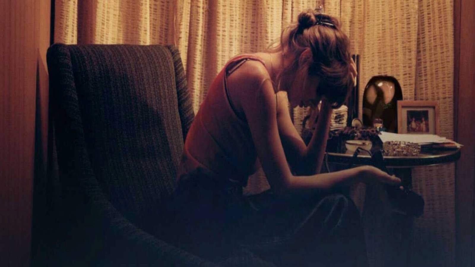 taylor swifts midnights sitting chair hand on head