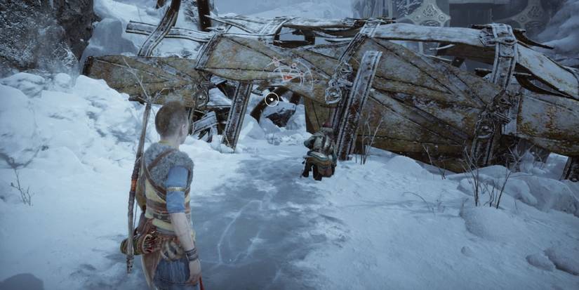 Atreus prepares to climb through a ruined structure in God of War Ragnarok