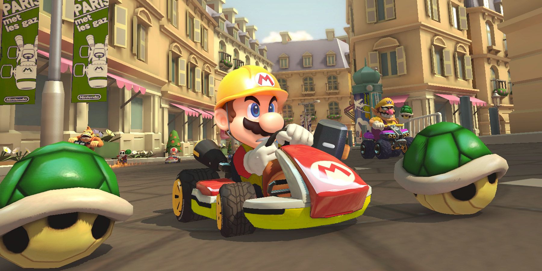 Mario driving a kart in the street by two green shells and Wario in the background in Mario Kart 8