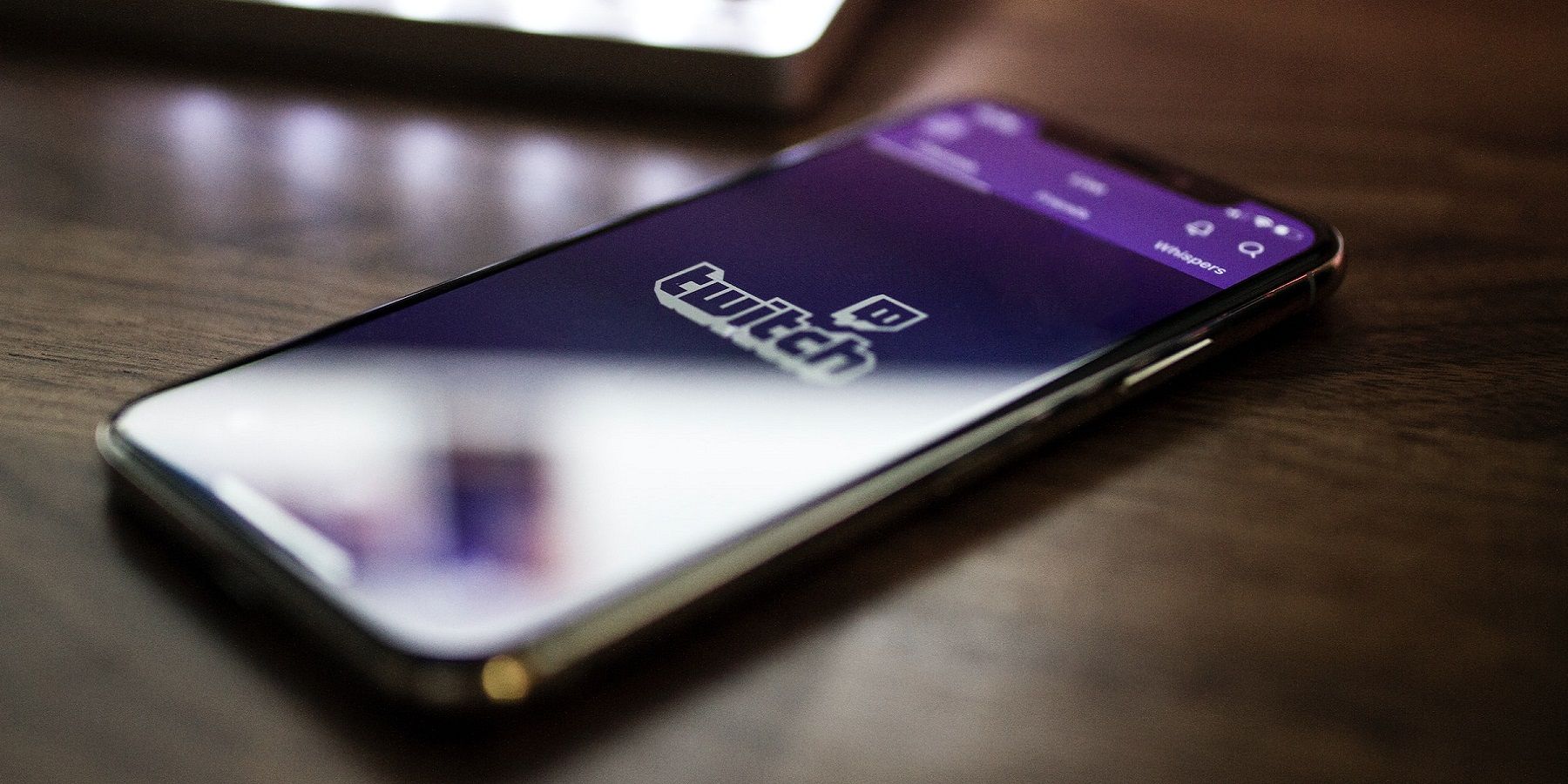Photo of a phone on a desk, with the Twitch logo on the phone's screen.