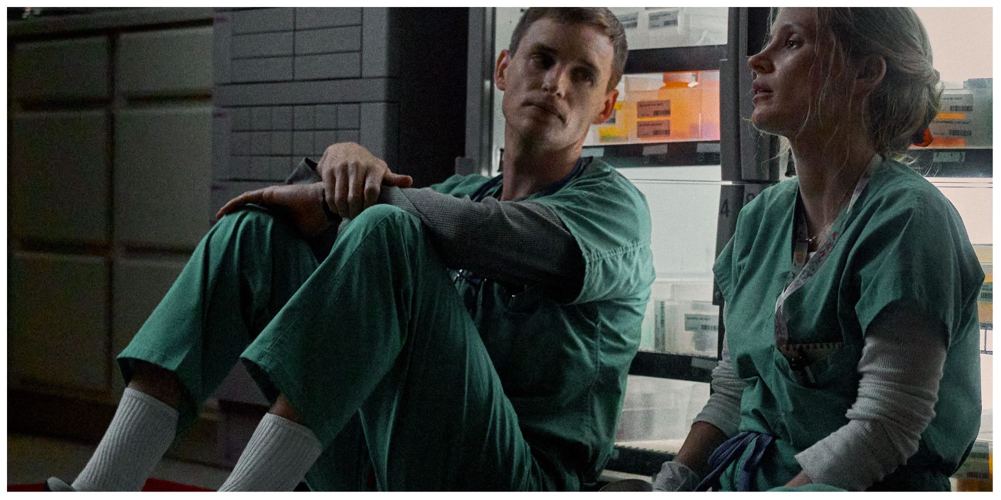 Eddy Redmayne and Jessica Chastain as nurses sat on the floor of a hospital in The Good Nurse