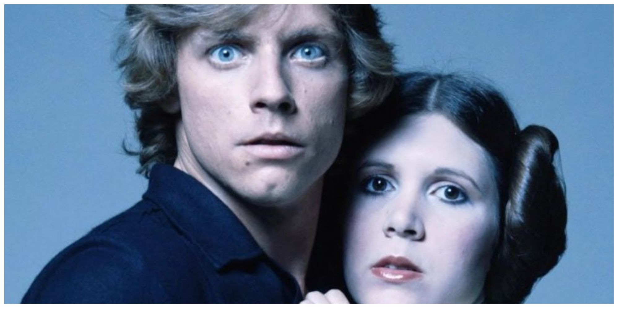 Luke and Leia in the original Star Wars franchise looking towards the camera, standing close together.