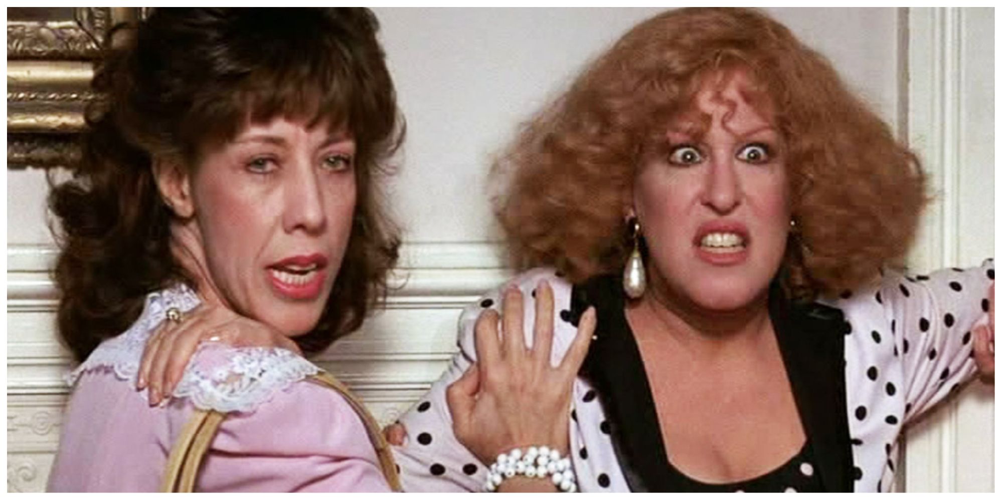 Lily Tomlin and Bette Midler starring in Big Business looking scared and leaning against a door