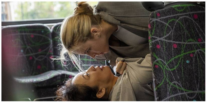 Villanelle pinning Eve down on a seat at the back of a double-decker bus