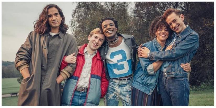 The key cast of It's A Sin hugging each other and smiling at the camera