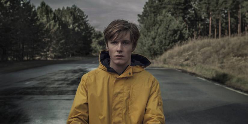 A boy wearing a yellow jacket and standing outside in Dark