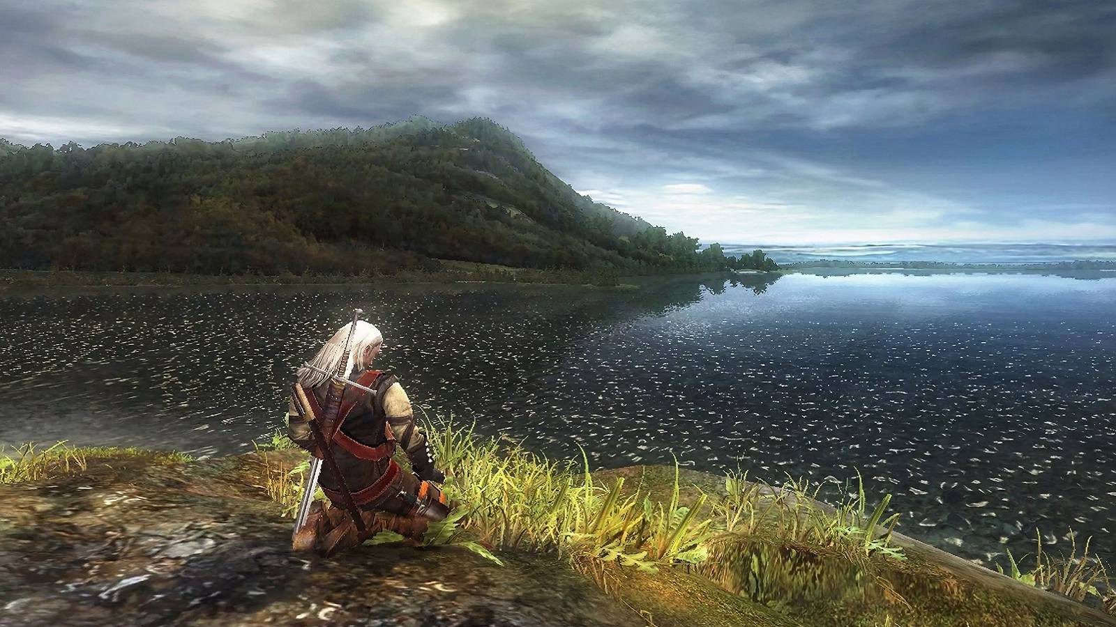 Image from the original The Witcher showing Geralt kneeling by a lake.