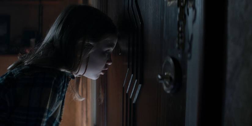 A_little_girl_looks_through_a_peephole_in_the_Evil_Dead_Rise_trailer