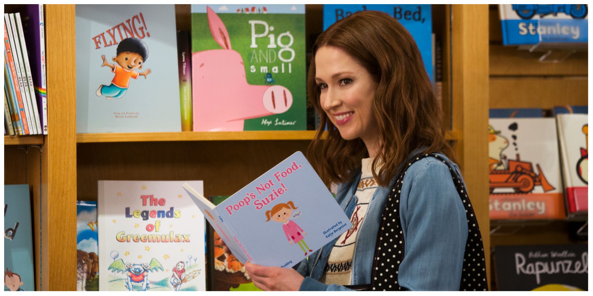Kimmy smiling whilst holding a book in the children's section of a bookstore 