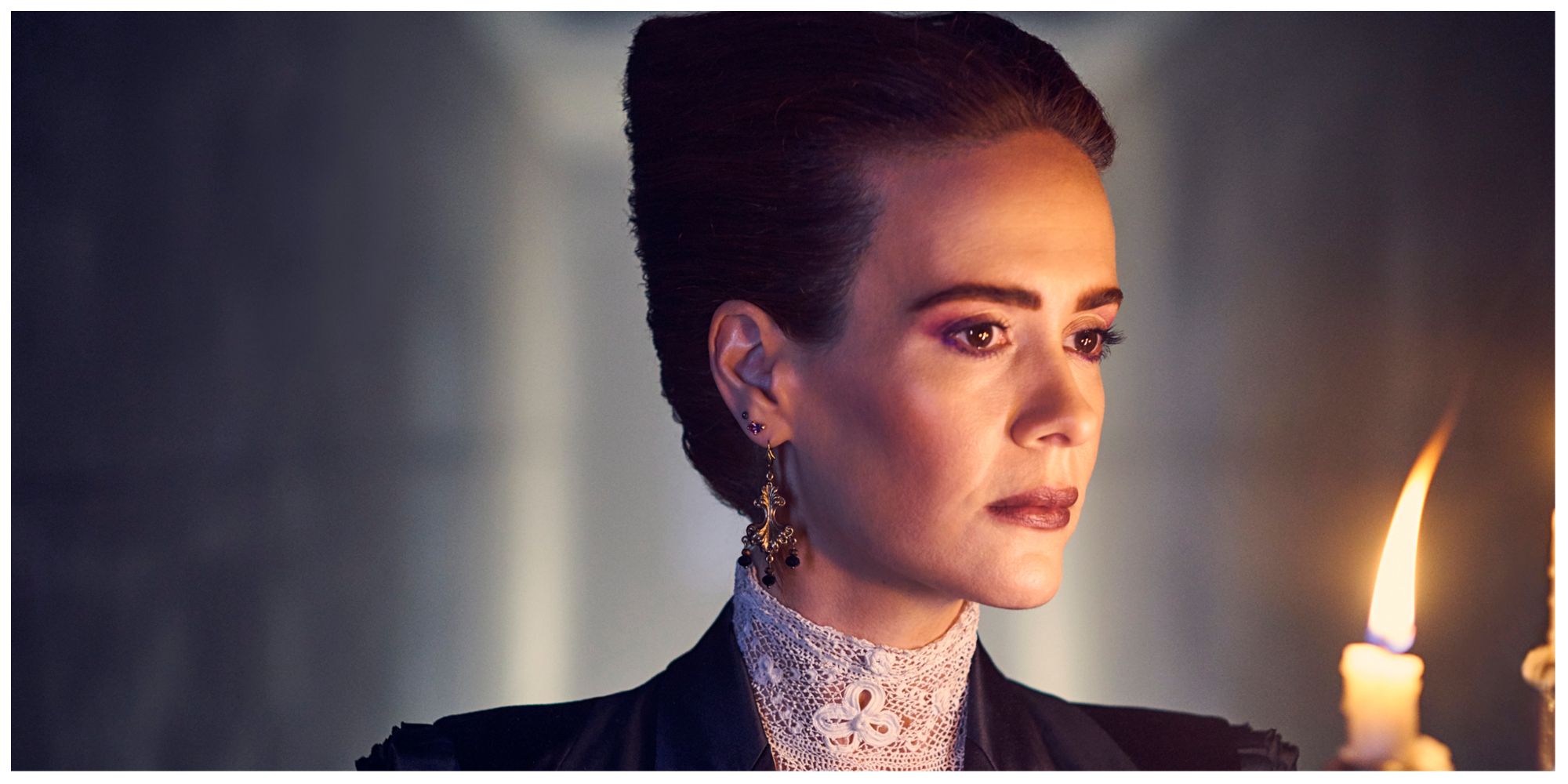 Sarah Paulson in American Horror Story with a candlestick in her hand. She looks serious.