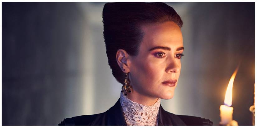 Sarah Paulson in American Horror Story with a candlestick in her hand. She looks serious.