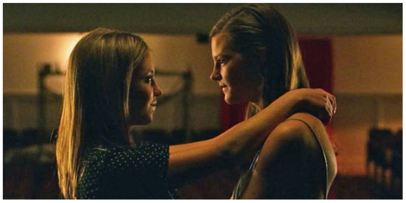 Kate and Emaline from Everything Sucks stood on an empty stage in each other's arms, looking at each other lovingly.