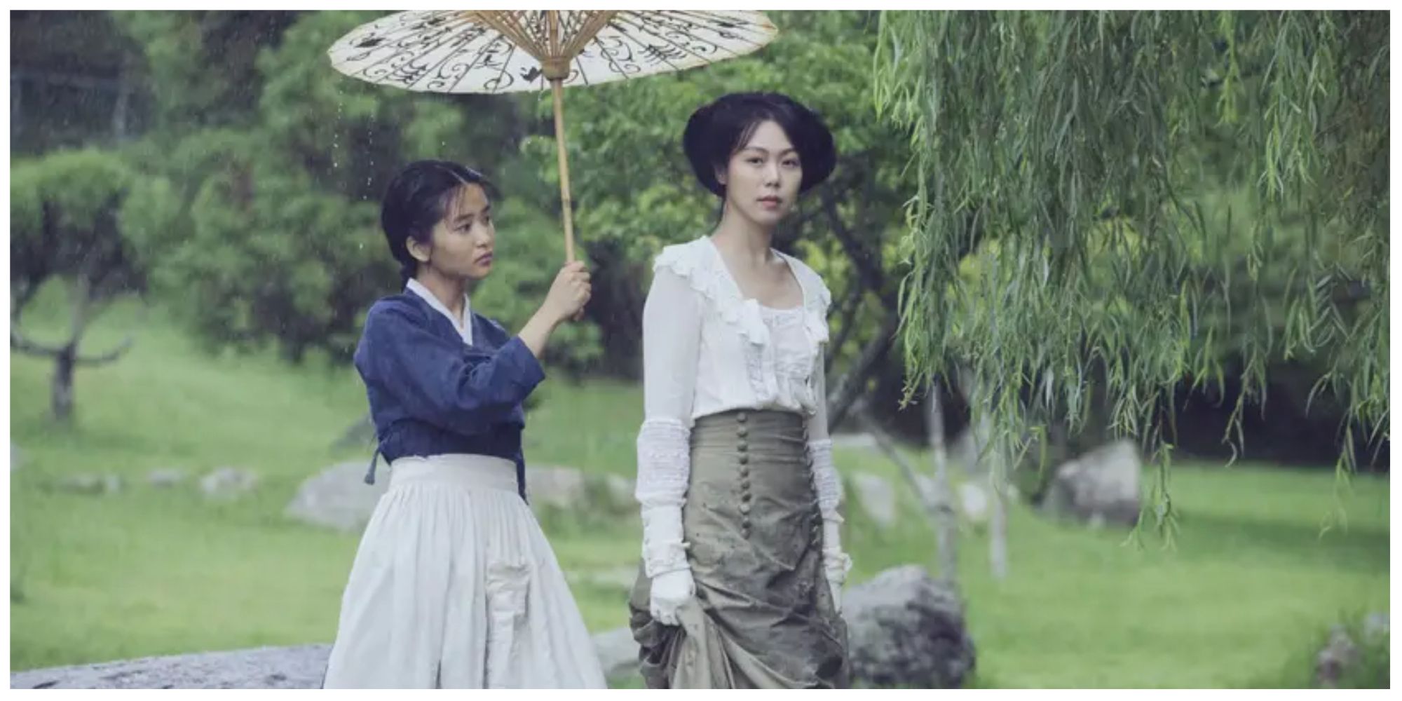 Sook-Hee holding a parasol over Lady Hideko, as she looks at her, in the garden